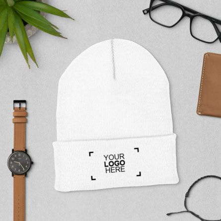Lifestyle sample embroidered custom winter hat laying flat surrounded by a watch and wallet 