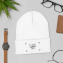 Esempio di un cappello invernale personalizzato ricamato che giace piatto circondato da un orologio e un portafoglio 
